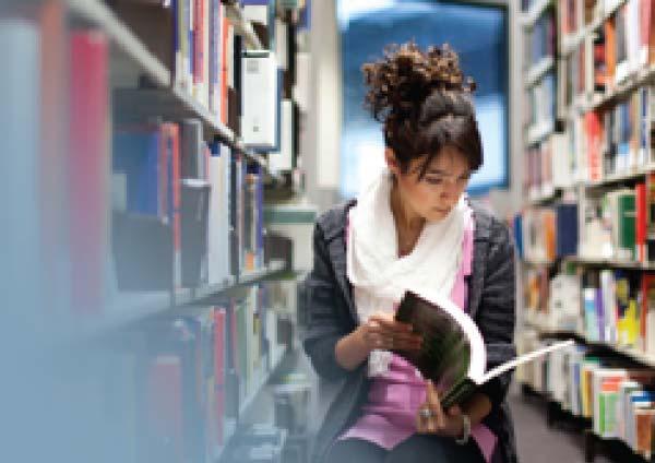 Student reads a book in a library. 
