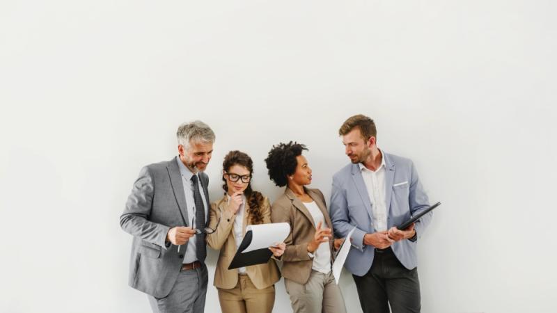 Four professional colleagues leaning against a wall