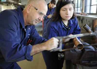 Plumbing tutor sawing through a piece of copper piping.