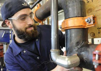 A fire safety VET student adjusting a water pipe.