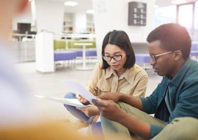 Two international students discuss a document. 