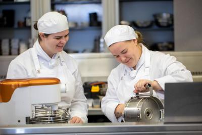 Two students in kitchen processing food