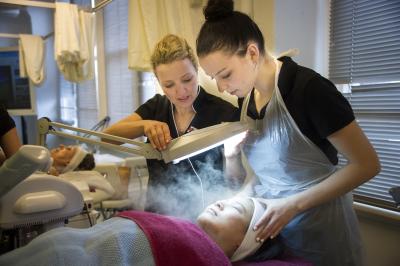 Beauty services student learning facial treatments from teacher