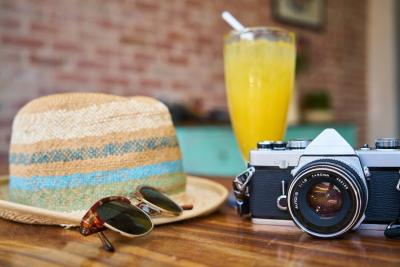 Holiday snapshot on table with each hat, sunglasses, tropical juice and a camera