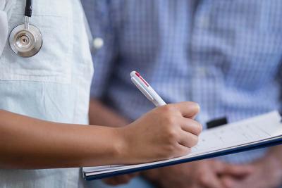 Doctor writing on clipboard with patient