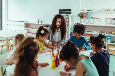 Early Childhood Education and Care (ECEC) teacher and students colouring at a table in a classroom
