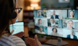 Back of woman engaging with people on laptop screen in an online webinar environment.